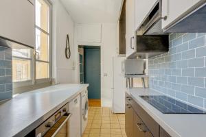 a kitchen with white counters and blue tiles at Aux Loges de L'orangerie in Versailles