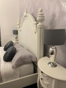 a white bed with a nightstand and a table with a lamp at Baytree House in Lowestoft