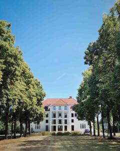 ein weißes Gebäude mit Bäumen davor in der Unterkunft DAS SCHMÖCKWITZ in Berlin