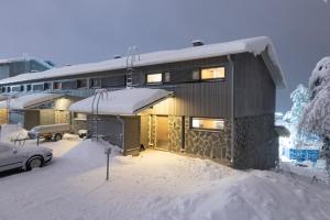 ein Haus mit Schnee auf dem Boden davor in der Unterkunft HolySuites 1 Ski-In & Ski-Out Holiday Home in Pyhätunturi