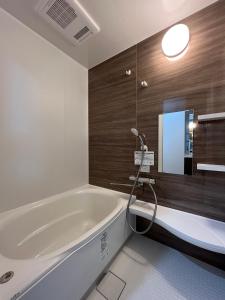 a bathroom with a large tub and a mirror at Furano Yukisachi House in Furano