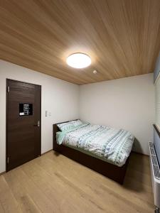 a bedroom with a bed and a wooden ceiling at Furano Yukisachi House in Furano