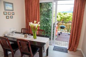 a dining room with a table with a vase of flowers at Rothesay in Knysna