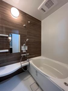 a bathroom with a bath tub and a sink at Furano Yukisachi House in Furano