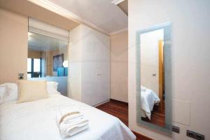 ヒホンにあるBahia Apartamentoの白いベッドと鏡のある寝室