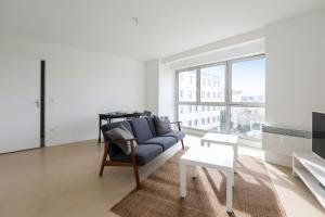 uma sala de estar com um sofá azul e uma grande janela em Spacious and calm apartment in Montrouge - Welkeys em Montrouge