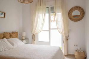 1 dormitorio con cama blanca y ventana en Mi pequeño rincón, en Los Caños de Meca