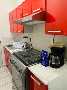 a kitchen with red cabinets and a stove top oven at Departamento nuevo en Aldea Tulum, alberca e internet in Tulum