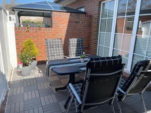 eine Terrasse mit einem Tisch, Stühlen und einem blauen Sonnenschirm in der Unterkunft Ferienwohnung Am Südstrand in Borkum