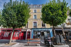 a building on a street with a bench and trees at Le Milady- Versailles in Versailles