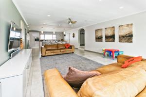 ein Wohnzimmer mit 2 Sofas und einer Küche in der Unterkunft Modern 4 bedroom residential villa with pool, fully solar powered in Sandton