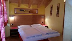 a small bedroom with a bed with white sheets at Chalet Heidi in Arabba