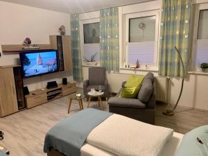 ein Wohnzimmer mit einem Bett, einem Sofa und einem TV in der Unterkunft Ferienwohnungen Marita in Salzwedel