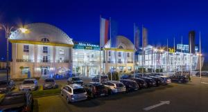 a large building with cars parked in a parking lot at Hotel Mazurkas in Ożarów Mazowiecki