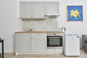 eine Küche mit weißen Schränken und einer Arbeitsplatte in der Unterkunft Drabika Apartment Balcony & Private Parking Wrocław by Noclegi Renters in Breslau