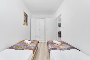 zwei Betten in einem Zimmer mit weißen Wänden in der Unterkunft Drabika Apartment Balcony & Private Parking Wrocław by Noclegi Renters in Breslau + 10 Fotos
