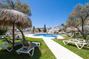 Grupa krzeseł i parasoli obok basenu w obiekcie Tropicana Townhouse, 2 bedroom w mieście Nerja
