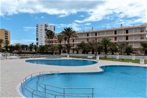 two swimming pools in front of a large building at Amazing views to Los Cristianos Bay in Achacay in Los Cristianos