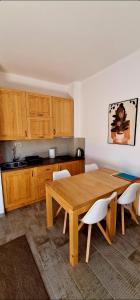- une cuisine avec une table en bois et des chaises blanches dans l'établissement Apartmani Aleksandra, à Kolašin