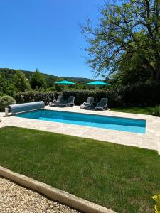 a swimming pool with chairs and umbrellas in a yard at La Dovecote Sarlat in Sarlat-la-Canéda