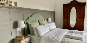 a bedroom with a bed with a green headboard and white pillows at Portman Lodge in Blandford Forum