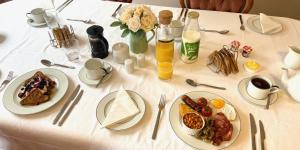 a white table with plates of breakfast food on it at Portman Lodge in Blandford Forum