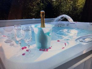 uma banheira de hidromassagem com copos de vinho e uma garrafa em La Lilloise Villeneuve D'Ascq GD STADE Mauroy em Villeneuve d'Ascq