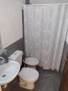 y baño con aseo, lavamanos y cortina de ducha. en Departamentos Tierra Colorada en La Rioja