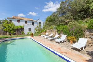 a swimming pool with lounge chairs and a house at Los Algarrobos Gaucin in Gaucín