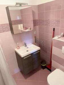 uma casa de banho rosa com um lavatório e um WC em Holiday Apartment em Nerezine