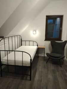 ein Schlafzimmer mit einem Bett, einem Stuhl und einem Fenster in der Unterkunft Antówka in Tolkmicko
