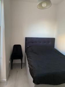 シュチェチンにあるApartamenty Przygodna Parkのベッドルーム(黒いベッド1台、椅子付)