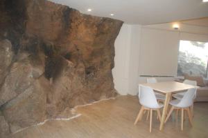 a table and chairs in a room with a rock wall at Koba, una experiencia memorable in Potrero de los Funes