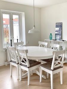 a white dining room with a white table and chairs at Familjevänligt hus med pool och tennisbana in Torekov