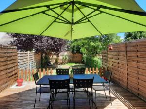 una mesa y sillas bajo una sombrilla verde en Maison Cheptainville AVEC TERRASSE SUR VERDURE, en Cheptainville