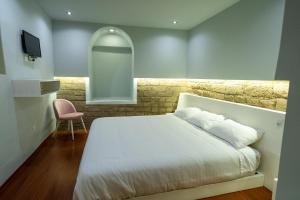 a bedroom with a white bed and a pink chair at CASA ANABELA HOTEL BOUTIQUE in Quito