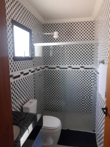 a bathroom with a white toilet and a window at Apartamento Duplex pé na areia em Boracéia in Bertioga