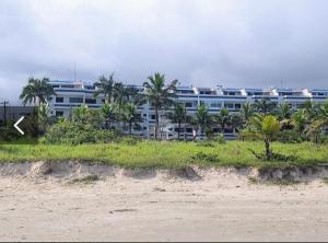 a large building with palm trees in front of a beach at Apartamento Duplex pé na areia em Boracéia in Bertioga