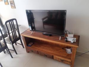 a flat screen tv sitting on top of a wooden stand at Apartamento Duplex pé na areia em Boracéia in Bertioga