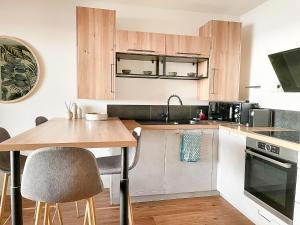 eine Küche mit Holzschränken und einem Holztisch in der Unterkunft Le Pétrel Bleu - Appartement sur la plage des Tortues à Saint-Leu in Saint-Leu