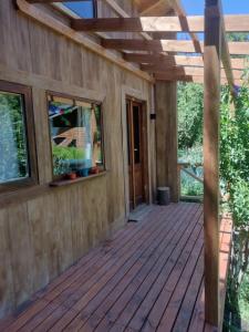 une maison avec une terrasse en bois et une pergola dans l'établissement Casa en entorno de bosque, cerca de playas y cerros, à San Carlos de Bariloche