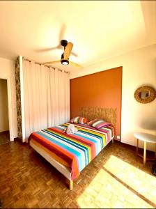 1 dormitorio con 1 cama con una manta a rayas de colores en Cosy Californie en Niza