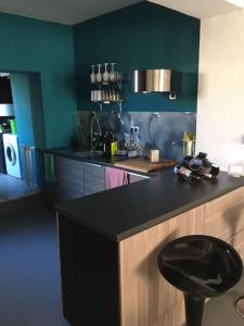 una cocina con encimera negra y taburete negro en Maison cosy en Remicourt