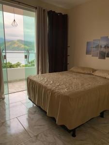 a bedroom with a bed and a large window at Casa com Praia no quintal in Angra dos Reis