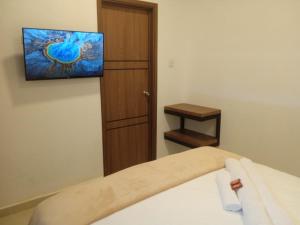 sypialnia z łóżkiem z telewizorem na ścianie w obiekcie Hotel El Baquiano w mieście San Juan de Arama
