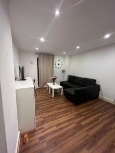 a living room with a black couch and wooden floors at Lovely luxury 1-Bed Apartment in Wembley in London