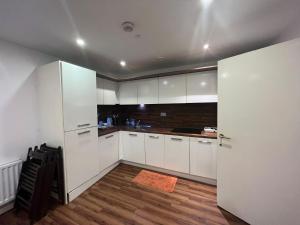 a kitchen with white cabinets and a wooden floor at Lovely luxury 1-Bed Apartment in Wembley in London