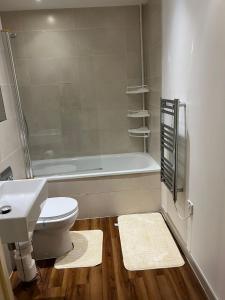 a bathroom with a toilet and a sink and a bath tub at Lovely luxury 1-Bed Apartment in Wembley in London