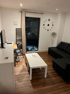 a living room with a table and a clock on the wall at Lovely luxury 1-Bed Apartment in Wembley in London