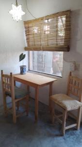 Casa de Kai Mazunte في مازونتي: طاولة خشبية مع نبات الفخار وكرسيين